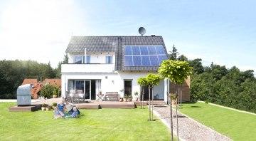 Familie sitzt im Garten auf der Wiese an einem sonnigen Tag und macht sich unabhängig und autark mit Heimspeicher sonnenBatterie und einer PV Solar Anlagae